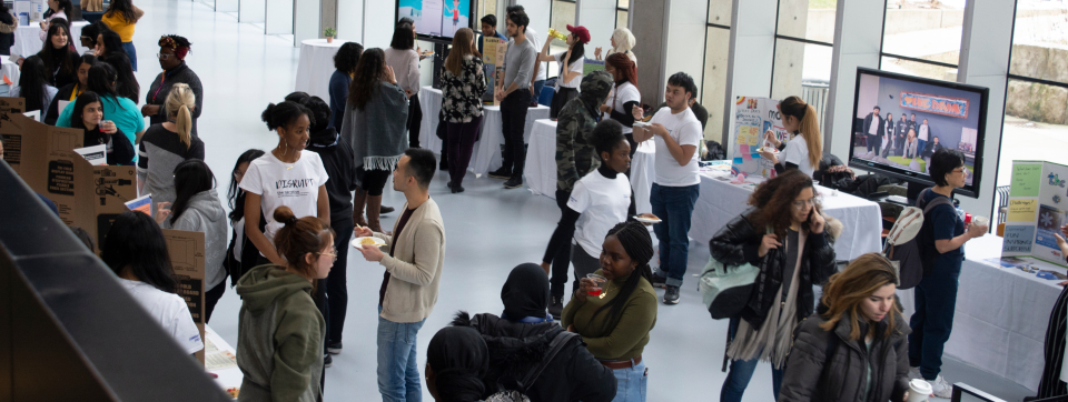 Students at various booths in an airy atrium.