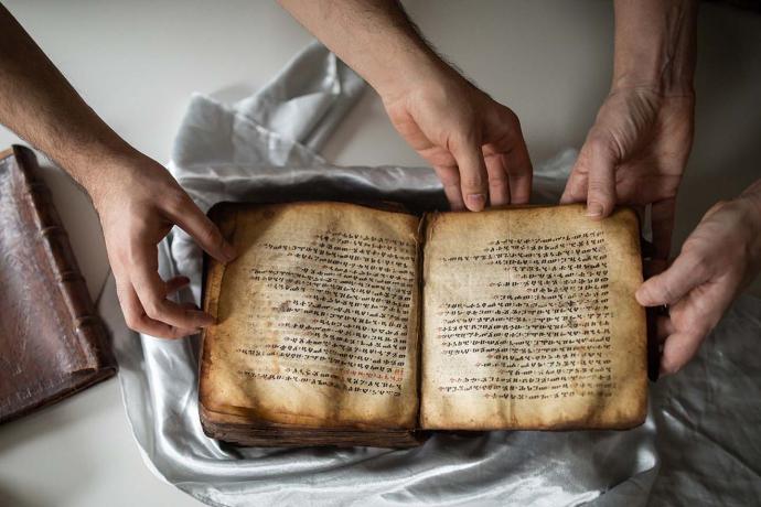 Hands holding an ancient manuscript