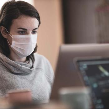 Woman wearing a mask and working in front of her laptop