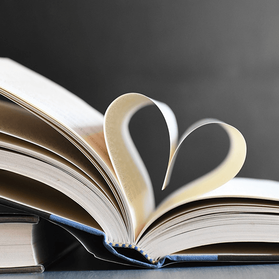 Open book lies on a table, pages shaped into a heart.