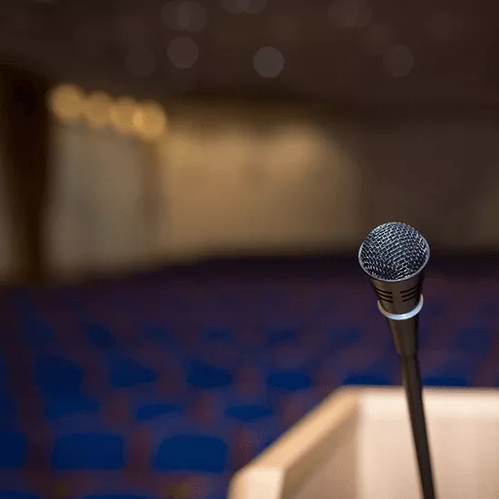 Close-up of a microphone with empty chairs in the background