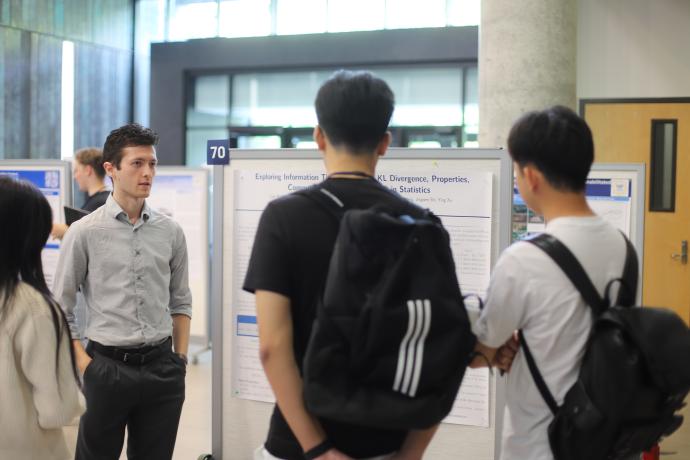 A poster presenter explains his research to fellow students.