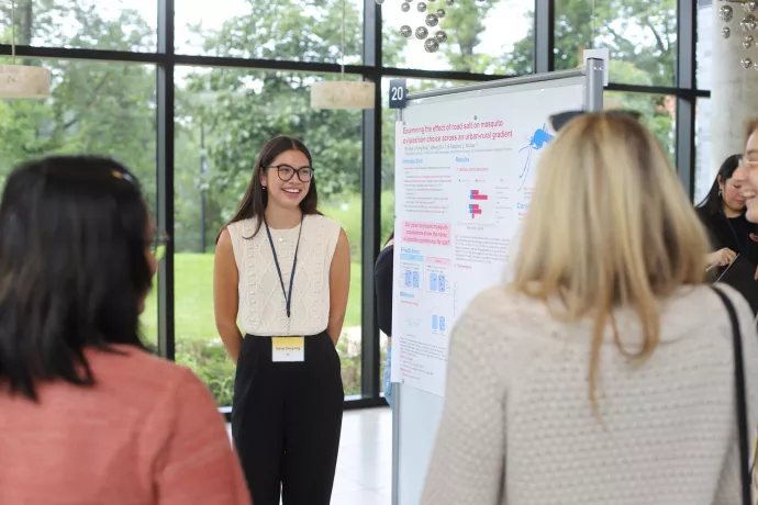 A poster presenter explains her research to fellow students.