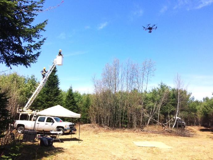 researchers in cherry picker monitoring drone