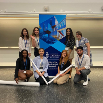 A group of students pose together in front of a bright blue OVPR banner.